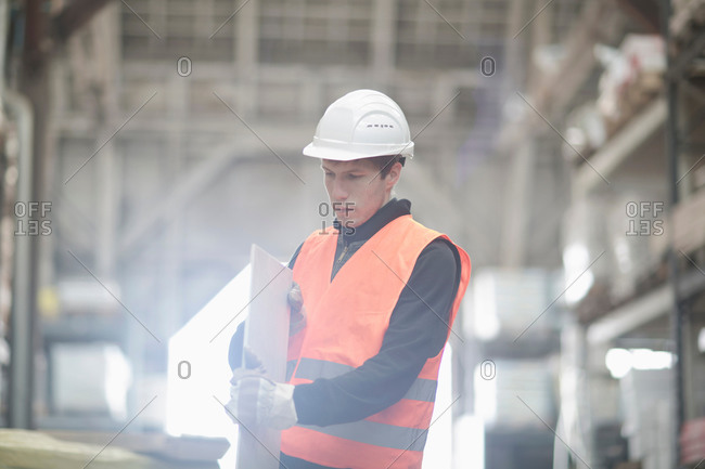 Young male warehouse worker examining plank in warehouse