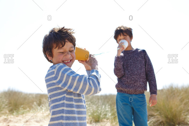Two young boys, playing with cup and string telephone
