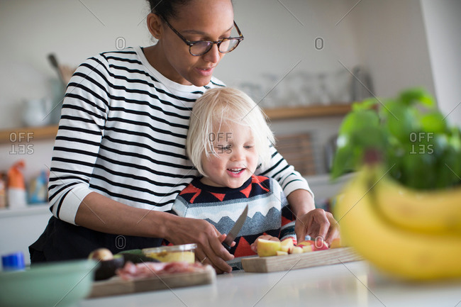 Mother helping son prep food in kitchen
