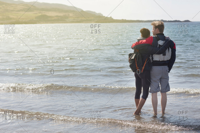 Mid adult couple with arms around each other on beach, Loch Eishort, Isle of Skye, Hebrides, Scotland