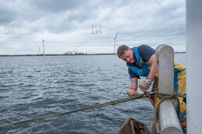 Fisherman tightening trawl line on research ship