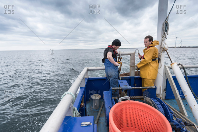 Research scientist and fisherman pay out trawl net on research ship