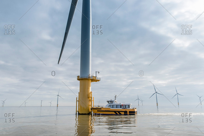 Engineers preparing to climb wind turbine from boat at offshore windfarm