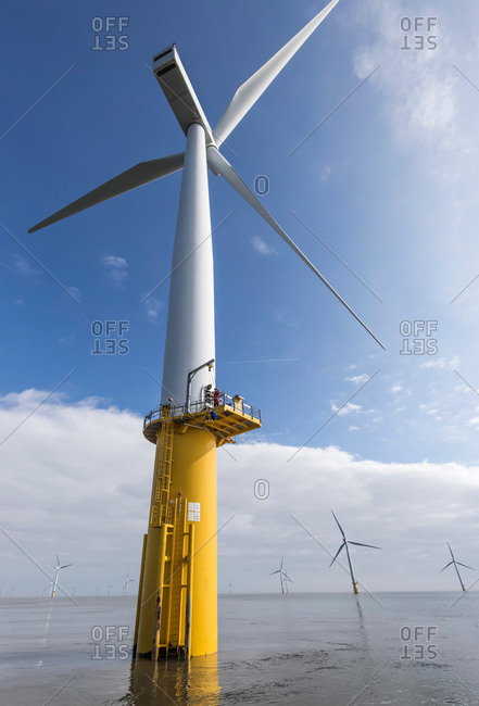 Engineer climbing wind turbine from boat at offshore windfarm