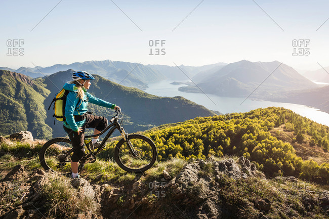 Young woman on mountain bike, looking at view, Lake Como, Italy