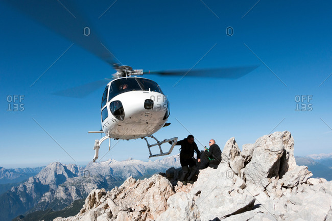 Helicopter dropping BASE jumpers on mountain, Dolomites, Italy