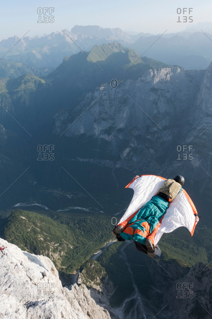 Male BASE jumper wingsuit flying from mountain, Dolomites, Italy