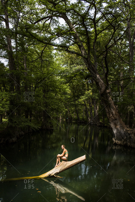 A young woman enjoys a calm swimming hole, the Blue Hole, near Wimberley, Texas.