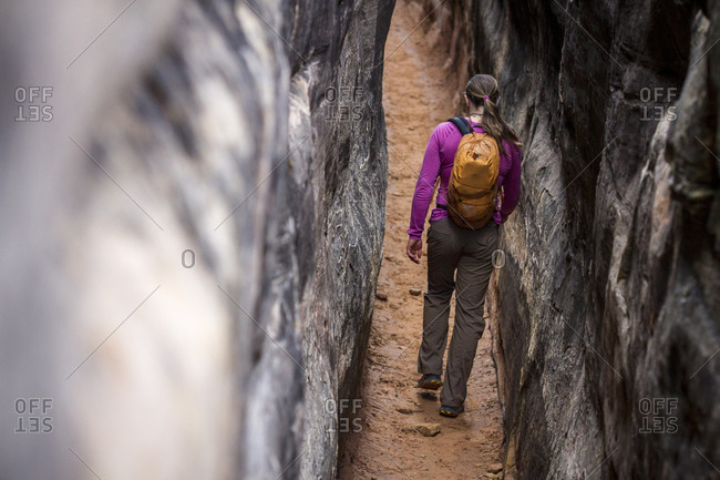 A woman hikes through a slot canyon in the Chesler Park are of Canyon lands National Park near Moab, Utah.