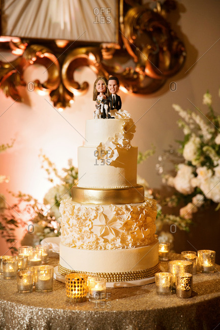 Gold decorated wedding cake with a topper with bride, groom and dogs
