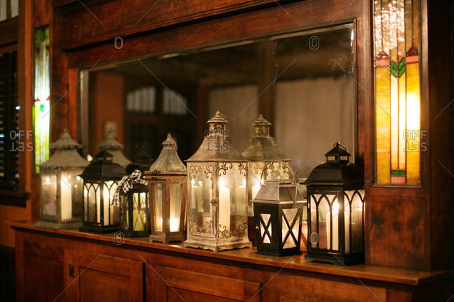 Antique lanterns sitting on a wood shelf in front of a mirror