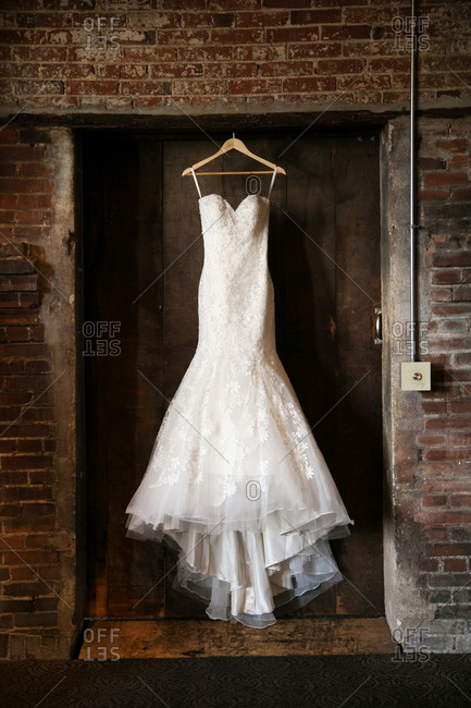Wedding dress hanging in a brick alcove
