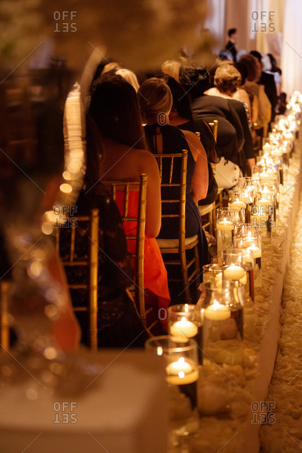 Guests at a wedding illuminated by votive candles