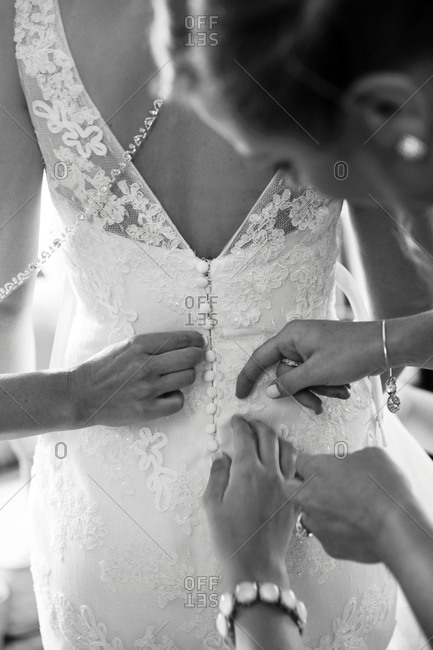 Bride\'s friends and family helping adjust the back of her dress