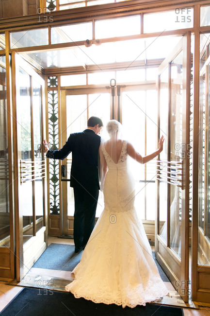 Newlywed couple walking out of an elegant lobby entrance
