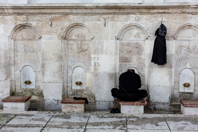 Man seated at washing spigots at the Blue Mosque in Istanbul, Turkey