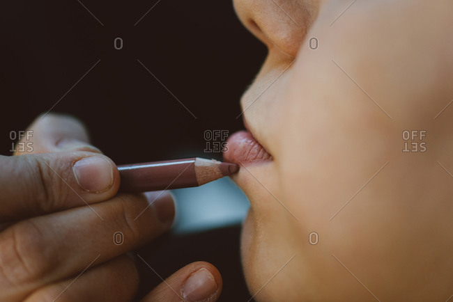 Close up of hand putting on lip liner with pencil