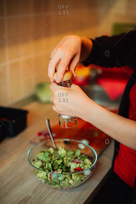 Woman grinding pepper onto a salad