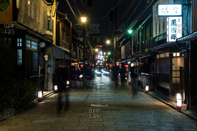 Silhouette of people walking along a street at night in Japan
