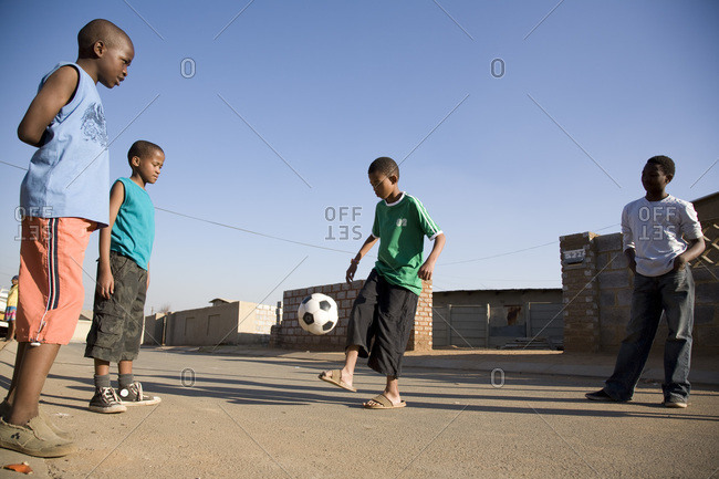 Boys playing soccer outside in the street