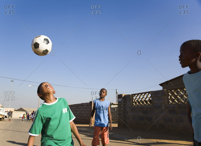 Boys playing soccer outside in the street