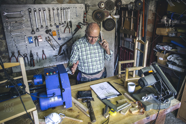 An older man talking on phone at workbench