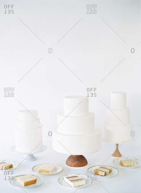 Three simple white three tier cakes with slices on plates