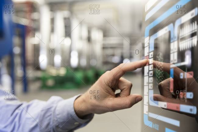 Man using touchscreen device in industrial plant