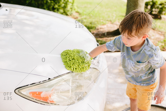 Boy washing a car in the driveway
