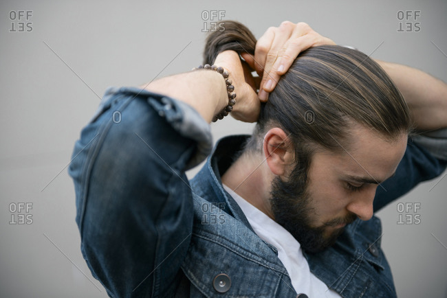 Man pulling his hair back into a ponytail