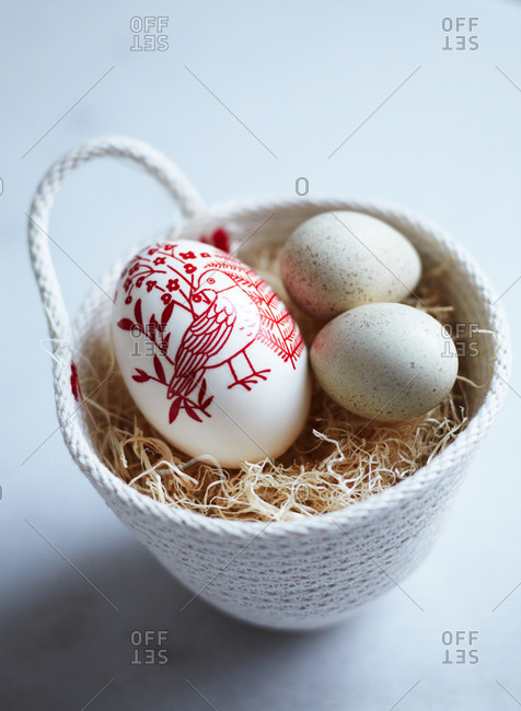 Easter eggs in a small woven basket with straw