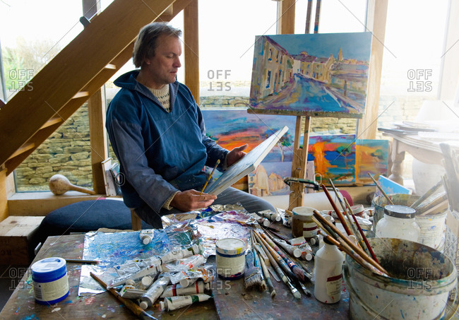 Portrait of artist examining painted canvas in studio