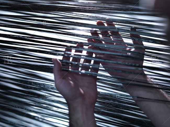Close up of hands holding carbon fibre on loom in carbon fibre factory