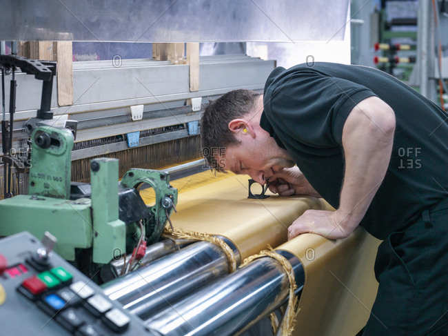 Worker inspecting kevlar fabric in carbon fibre factory