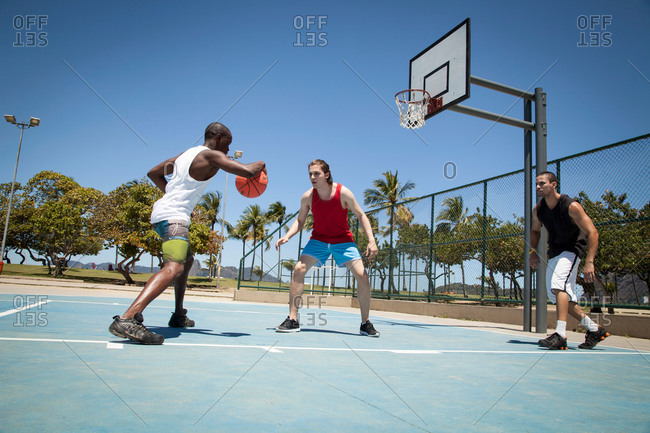 Three men practicing basketball on basketball court