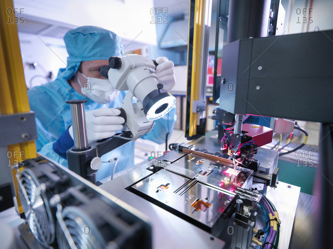 Electronics worker checking component in clean room