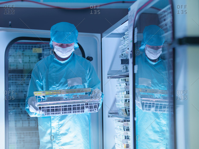 Worker checking archived electronic components in nitrogen atmosphere in clean room laboratory