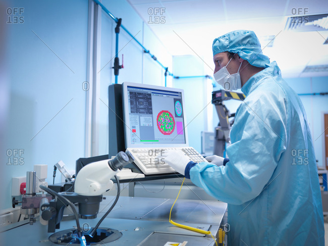 Electronics worker checking silicon wafer in clean room laboratory