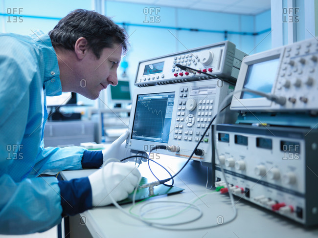 Worker checking electronics in clean room laboratory