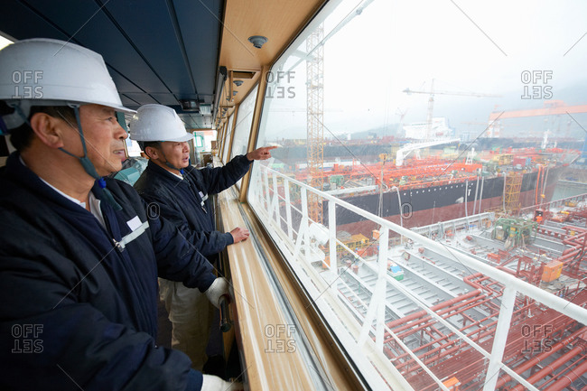 Workers having discussion overlooking shipping port, GoSeong-gun, South Korea