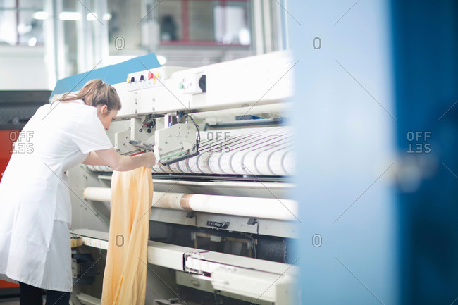 Woman working at machinery in laundry