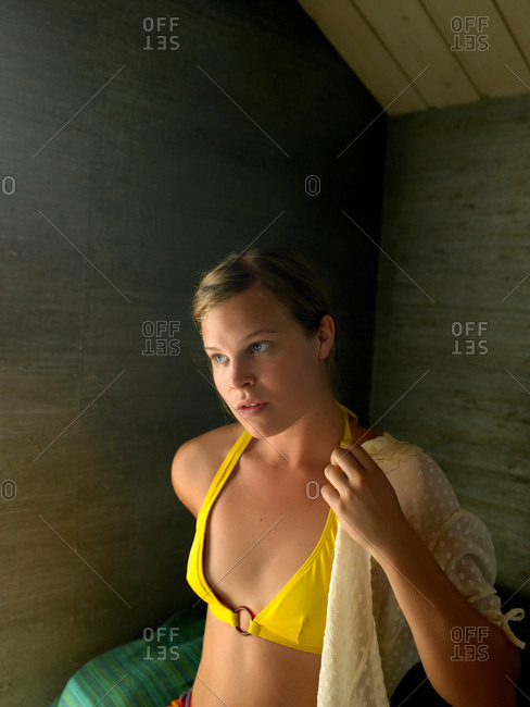 Portrait of young woman putting on blouse over bikini top