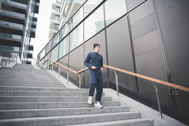 Young male runner moving down city stairs
