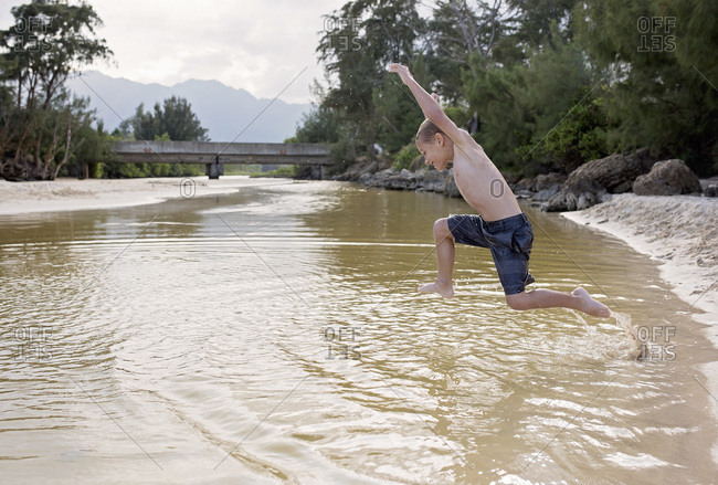 Little boy jumping into a river
