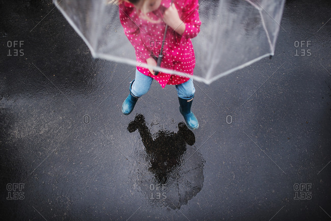 Overhead view of girl jumping with clear umbrella