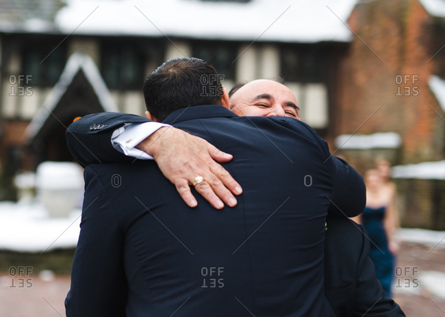 Groom and father-in-law embrace on wedding day