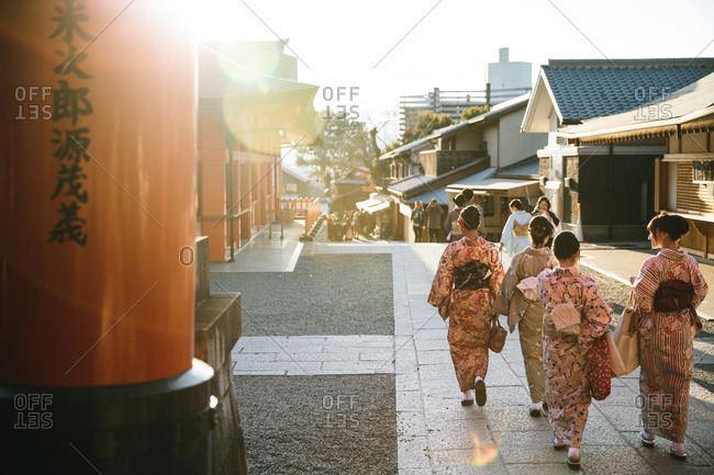 A group of Japanese women dressed in kimono's walking outdoors at sunset