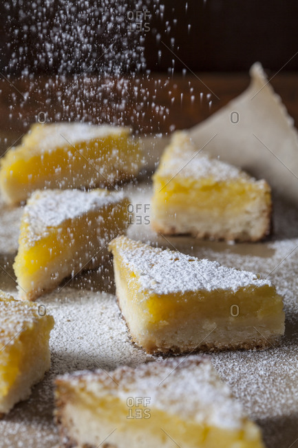 Lemon dessert wedges being sprinkled with powdered sugar