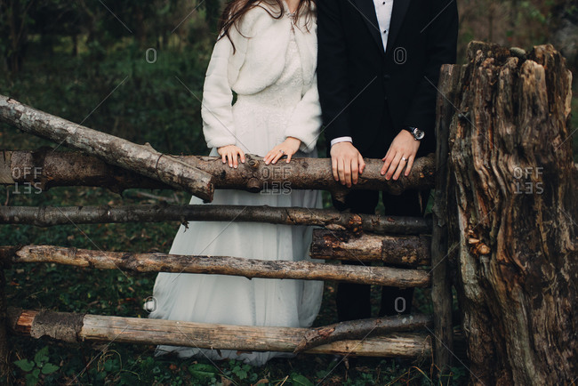Bride and groom standing by a fence made of tree logs