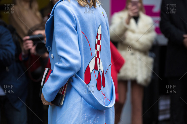 Woman wearing a blue coat with a rocket ship on the back